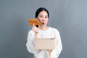 jonge Aziatische vrouw met blij gezicht en geniet van het eten van gebakken kip foto