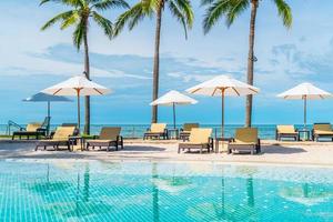 prachtig tropisch strand en zee met parasol en stoel rond zwembad in hotelresort foto