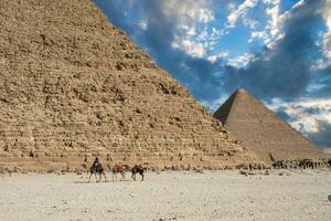 een groep van mensen rijden kamelen in voorkant van de Super goed piramide foto