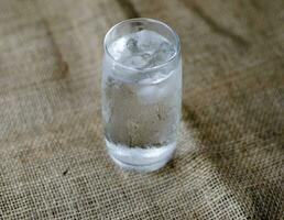 dichtbij omhoog, verkoudheid drinken water met ijs in een schoon glas, drinken gezond en koel omlaag. foto