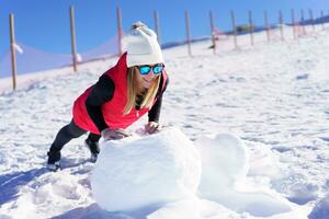 gelukkig vrouw aan het doen oefening in warm kleren Aan sneeuw rots foto