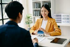 vrouw echt landgoed middel is gebruik handen naar beschermen rood dak voor de concept van echt landgoed investering over huis handel, aankoop Bij bureau in kantoor foto