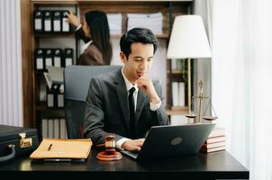 Aziatisch advocaat Mens werken met een laptop en tablet in een wet kantoor. wettelijk en wettelijk onderhoud concept. op zoek Bij camera in modern kantoor foto