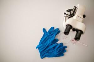 medisch handschoenen en microscoop zijn geplaatst op tafel in laboratorium naar bereiden virologen wie willen naar gebruik laboratorium naar onderzoeken monsters van virus ze ontvangen van epidemie. medisch uitrusting voor gebruik in laboratorium foto