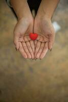 een klein rood hart symboliseert de liefde, vriendelijkheid en vriendschap dat een jong vrouw aanbiedingen naar iemand. concept van gebruik makend van harten net zo een symbool van liefde, vriendschap, vriendelijkheid en medeleven. foto