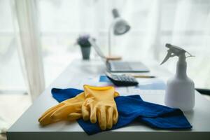 blauw handdoek en geel handschoenen waren geplaatst Aan houten tafel voor schoonmaak personeel naar gebruik naar schoon en voorkomen schoonmaakster van dermatitis. concept van kiezen schoonmaak bedrijf naar schoon de kantoor foto