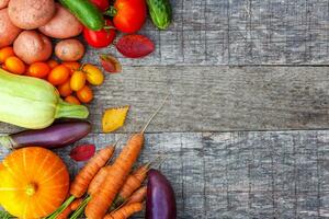 assortiment verschillende verse biologische groenten op landelijke stijl houten achtergrond. gezond voedsel veganistisch vegetarisch dieetconcept. lokale tuin produceert schoon voedsel. frame bovenaanzicht plat lag kopieerruimte. foto