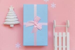 eenvoudig minimaal samenstelling winter voorwerpen ornament Spar boom slee geschenk doos geïsoleerd Aan roze pastel modieus achtergrond foto