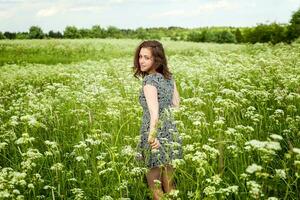 schoonheid meisje buitenshuis genieten van natuur. mooi vrouw jumping Aan zomer veld- met bloeiend wild bloemen, zon licht. vrij gelukkig vrouw. foto