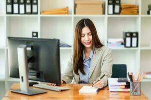 mooi Aziatisch bedrijf vrouw typen laptop en tablet geplaatst Bij de tafel Bij de kantoor foto
