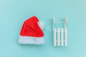 eenvoudig minimaal samenstelling Kerstmis de kerstman claus hoed slee geïsoleerd Aan blauw pastel kleurrijk modieus achtergrond foto