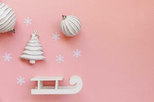 eenvoudig minimaal samenstelling winter voorwerpen ornament bal Spar boom slee geïsoleerd Aan roze pastel modieus achtergrond foto