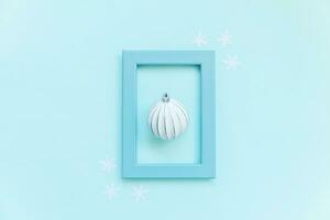 eenvoudig minimaal samenstelling winter voorwerpen ornament bal in blauw kader geïsoleerd Aan blauw pastel modieus achtergrond foto