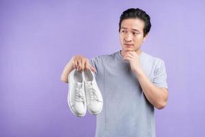 Aziatische man met sneakers op paarse achtergrond foto