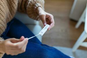 jong Afrikaanse vrouw Holding zelf testen zelf beheerd wattenstaafje en medisch buis voor coronavirus covid19, voordat wezen zelf getest Bij huis foto