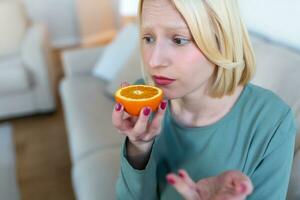 ziek vrouw proberen naar zin geur van voor de helft vers oranje, heeft symptomen van covid19, corona virus infectie - verlies van geur en smaak. een van de hoofd tekens van de ziekte. foto