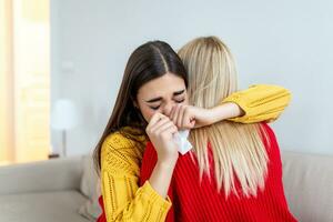 condoleance en ondersteuning concept. zorgzaam vrouw knuffelen haar huilen vriendin, geruststellend haar na ontvangen slecht nieuws foto