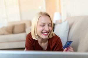 afbeelding tonen mooi vrouw boodschappen doen online met credit kaart. vrouw Holding credit kaart en gebruik makend van laptop. online boodschappen doen concept foto