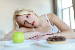 dieet of mooi zo Gezondheid concept. jong vrouw afwijzen rommel voedsel of ongezond voedsel zo net zo donut of toetje en kiezen gezond voedsel zo net zo vers fruit of groente. foto