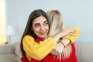 openhartig verschillend meisjes het beste vrienden omarmen staand binnenshuis, dichtbij omhoog tevreden Dames gezicht genieten inschrijving moment gemist blij naar zien elk andere na lang scheiding foto