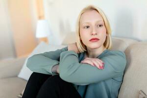 portret van een glimlachen jong vrouw ontspannende alleen Aan haar leven kamer sofa Bij huis in de middag foto