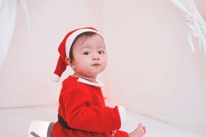 Aziatisch babymeisje in een kerstmankostuum. mooie kleine baby viert kerst. kerst baby.