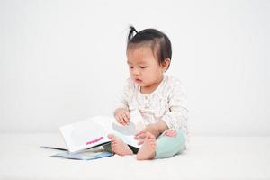 portret van Aziatische babymeisje, het lezen van een verhalenboek. foto