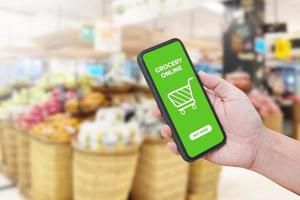 man hand met smartphone tegen bokeh van winkel achtergrond wazig. boodschappen online. foto