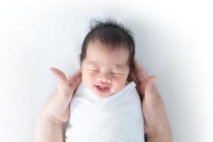 de pasgeboren baby lacht in de handen van de moeder. foto