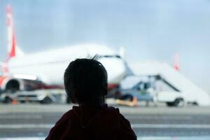 kleine jongen vliegtuigen kijken op de luchthaven foto