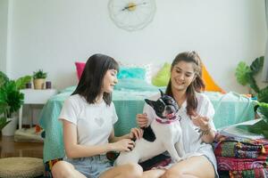 twee mooi Dames zittend Bij huis terwijl spelen met hun honden. foto