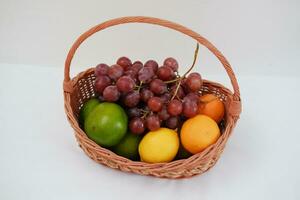 fruit in een mand Aan een wit achtergrond. oranje, druif, citroen. foto
