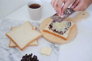 vrouw handen maken geroosterd brood met boter en chocola Aan wit achtergrond. foto