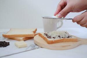 vrouw handen maken geroosterd brood met boter en chocola Aan wit achtergrond. foto