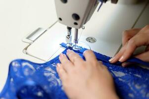 handen van een vrouw naaien blauw kleding stof foto