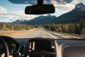 weg reis met auto het rijden met rotsachtig bergen Aan snelweg in banff nationaal park foto