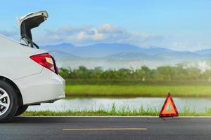 problemen auto en een rode driehoek waarschuwingsbord op de weg foto