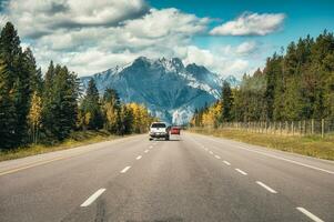 auto het rijden Aan snelweg naar rotsachtig bergen in herfst Woud Bij nationaal park foto