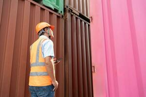 Aziatisch vrouw ingenieur met Notitie klembord en Aziatisch Mens leidinggevende in moeilijk hoeden en veiligheid vesten staan in houder terminal. houder in exporteren en importeren bedrijf en logistiek. foto