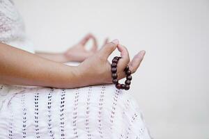 zwart kralen armband in vrouw hand- gedurende aan het doen meditatie. maken concentratie door tellen kralen. concept, cultuur van vertrouwen. religieus amulet. meditatie opleiding. mentaal gezondheidszorg foto