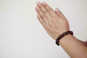 dichtbij omhoog hand- draagt kralen armband Doen hand- teken voor bidden gebaar. concept, mode accessoires. religieus amulet voor geluk, kan worden gebruikt in aan het doen meditatie of bidden ritueel. cultuur van vertrouwen. foto