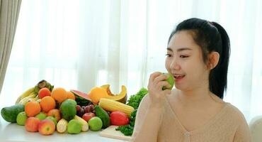 portret vrouwen hand met appel fruit met diverse verse rijpe groenten en fruit op tafel bij witte gordijn achtergrond foto