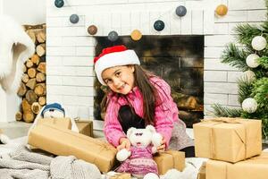 portret van mooi weinig meisje in de buurt een haard in Kerstmis foto