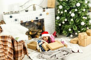 portret van mooi weinig meisje in de buurt een haard in Kerstmis foto