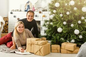 mooi hoor liefde paar zittend Aan tapijt in voorkant van haard. vrouw en Mens vieren Kerstmis foto