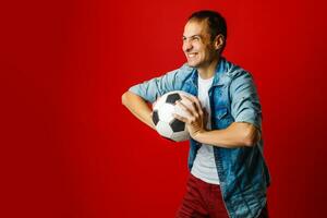 knap Mens Holding een voetbal bal over- kleurrijk achtergrondkleur foto