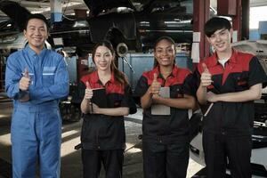 portret van multiraciaal professioneel monteur team duimen omhoog en kijken Bij camera, werk Bij auto onderhoud garage, gelukkig onderhoud banen, controleren en reparatie bezetting in automotive industrie bedrijf. foto