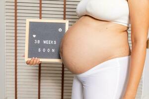 groot zwanger vrouw met brief bord foto