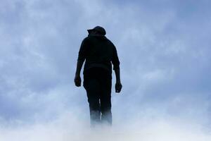 Mens silhouet tussen wolken in de berg foto