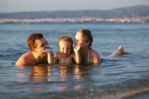 lachend weinig jongen met zijn ouders Bij de zee foto